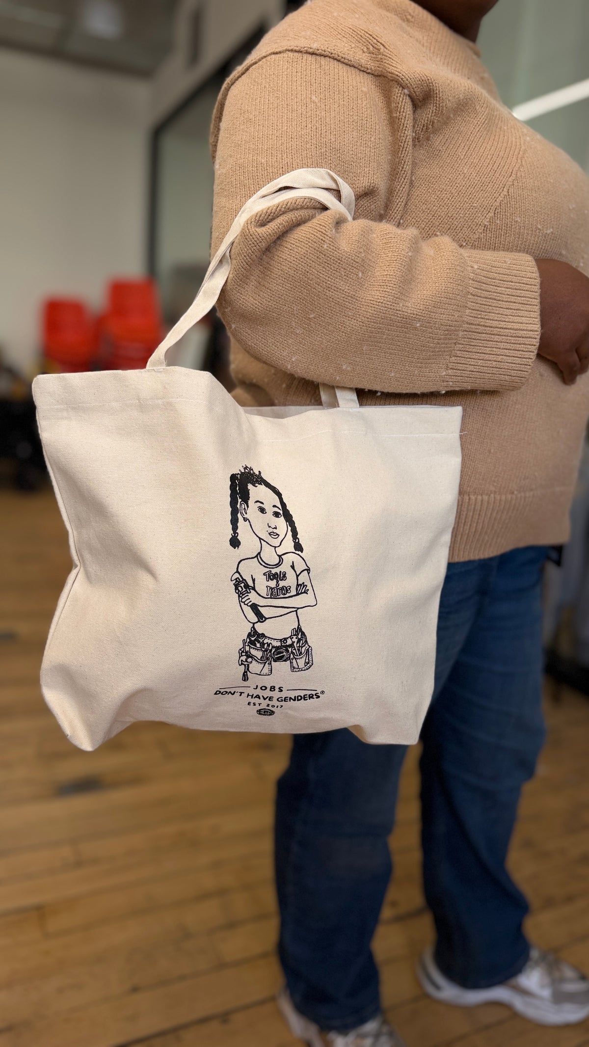 Person holding the Jobs Don't Have Genders® off-white canvas tote bag from Tools & Tiaras®, another view