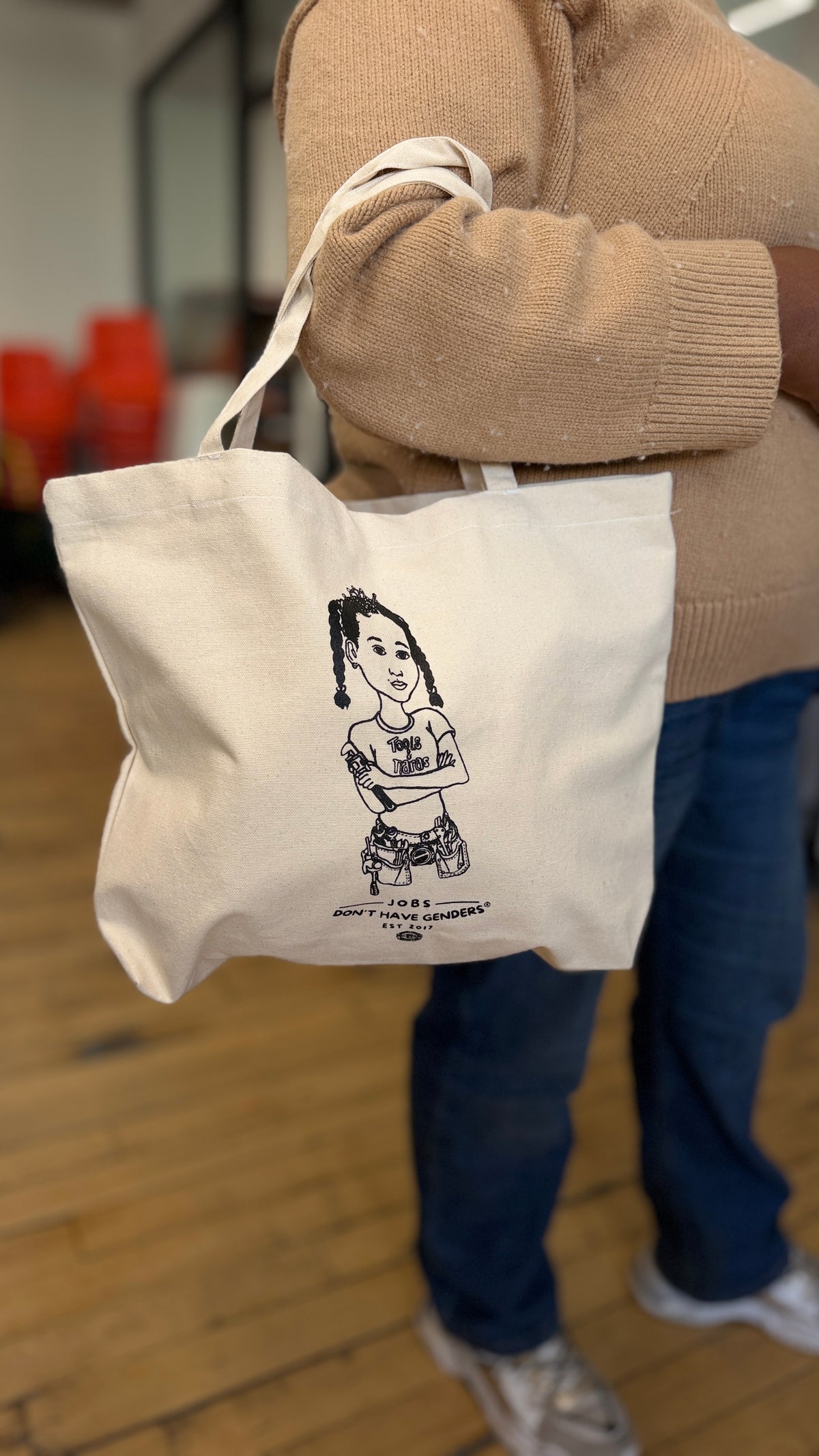 Person holding the Jobs Don't Have Genders® off-white canvas tote bag from Tools & Tiaras®, third view